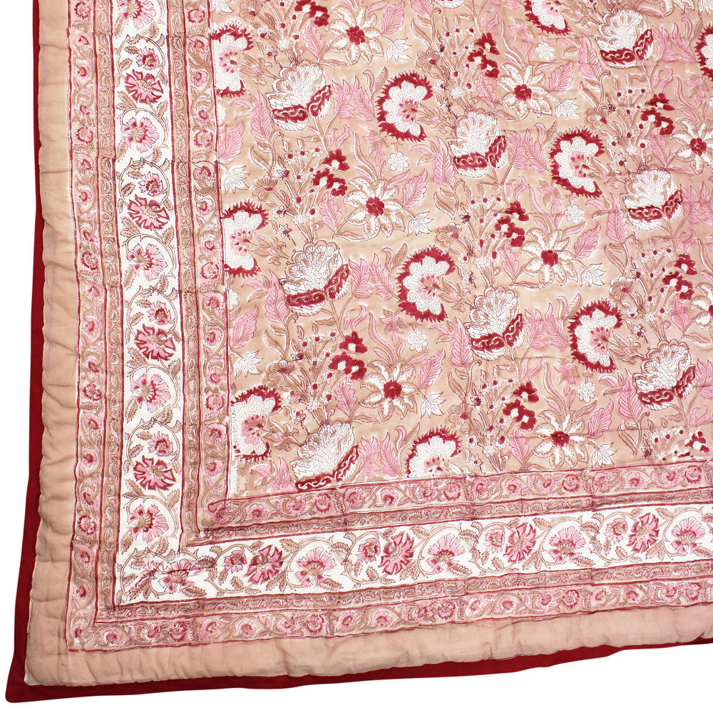 Pink and red reversible quilted throw in floral print.