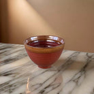 Rust coloured ceramic bowl with brown edge.