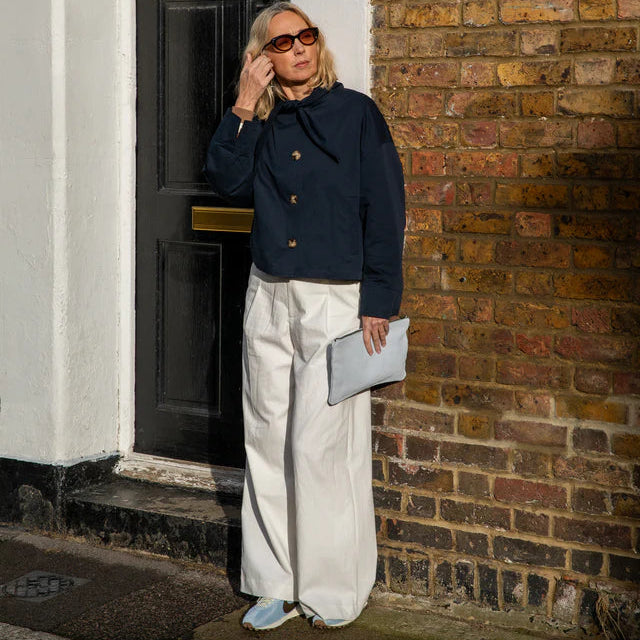 woman wearing navy jacket standing outside a door
