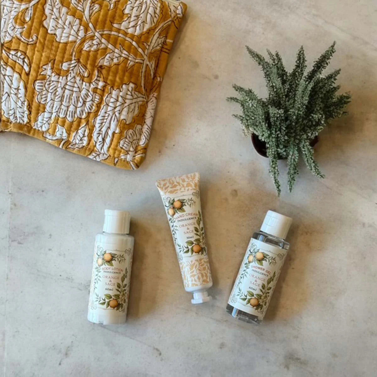 Weekend Kit. Three skincare products; hand cream, shower gel and body lotion,  on a textured surface with block printed cotton pouch.