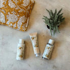 Weekend Kit. Three skincare products; hand cream, shower gel and body lotion,  on a textured surface with block printed cotton pouch.