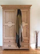 Luxurious mohair throw made in Scotland using traditional technique in honeycomb colours of ochre, grey and brown hanging from door of antique pine wardrobe..