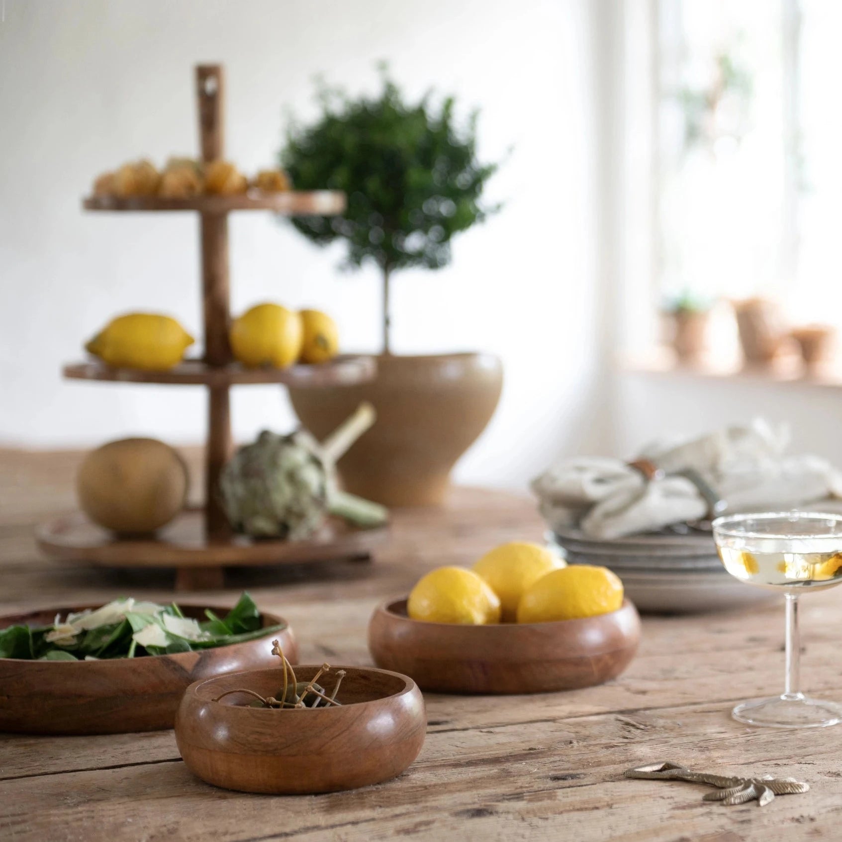 Wooden bowls with lemons on a wooden table, with a blurred background of a kitchen.