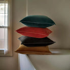Selection of square velvet cushions in green, rust, black and brown.