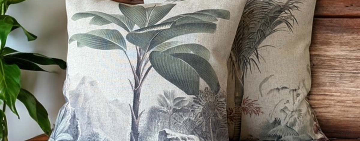 Decorative pillows with botanical patterns on a wooden bench.