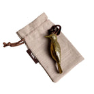 Brass woodpecker-shaped hanging ornament on linen gift bag.
